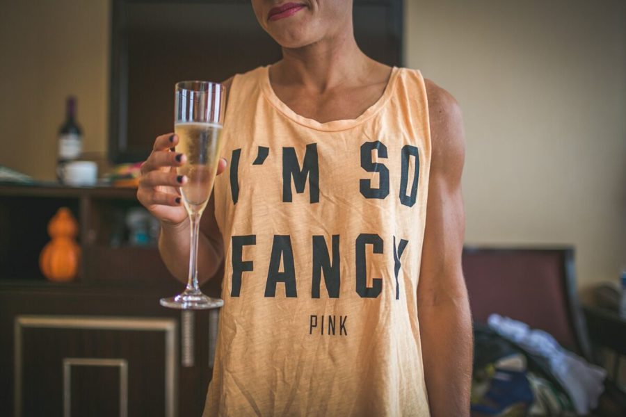 Woman holds glass of champagne while wearing a shirt that reads I'm So Fancy