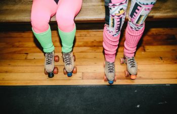 Women's legs with bright tights, leg warmers, and roller skates