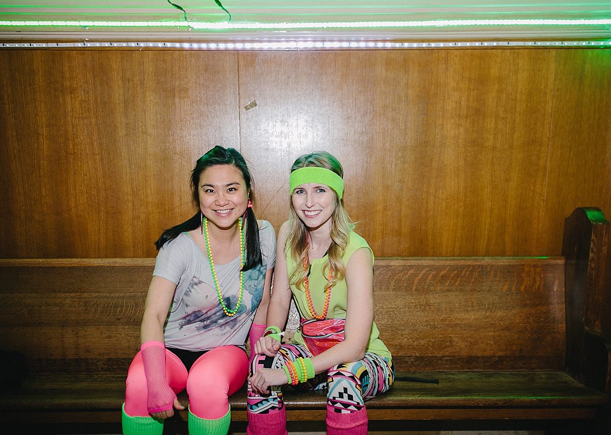 two women sit on a church pew in brightly colored clothes