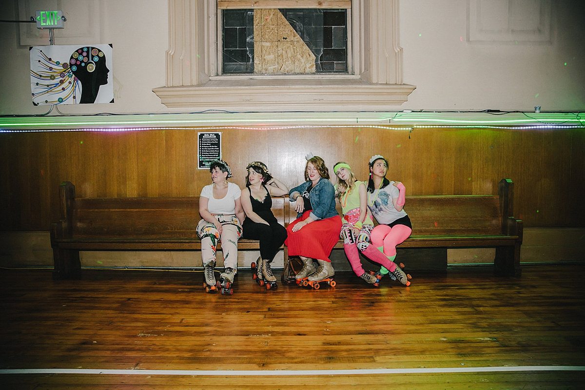 women sit on a church pew, looking cool AF, wearing roller skates