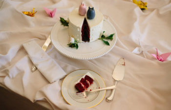 Slice of cut red velvet wedding cake on a table with flowers and white tablecloth