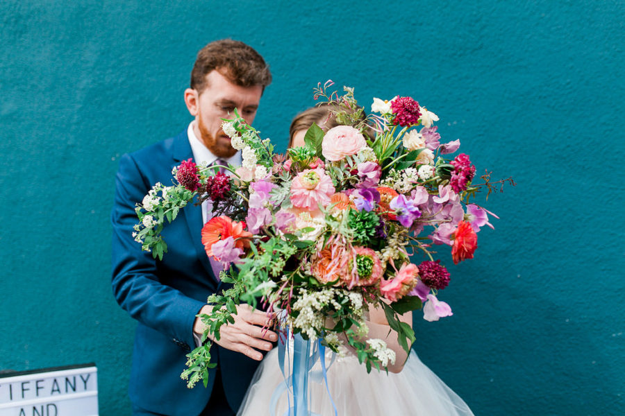 Bride and groom with an enormous bouquet in front of their faces