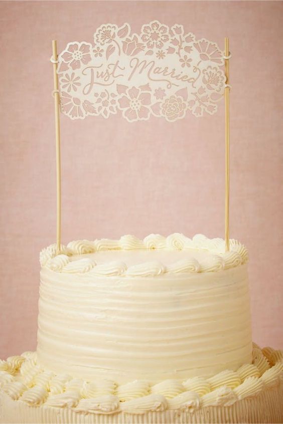 laser cut white cake topper reads "Just Married" with flowers