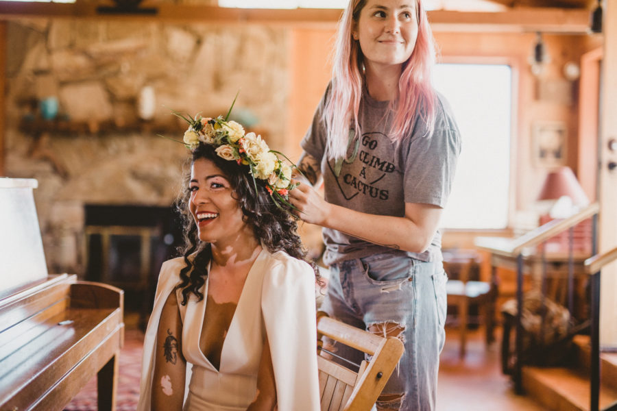 A woman smiles at you as she has her wedding hairstyle done with a flower crown