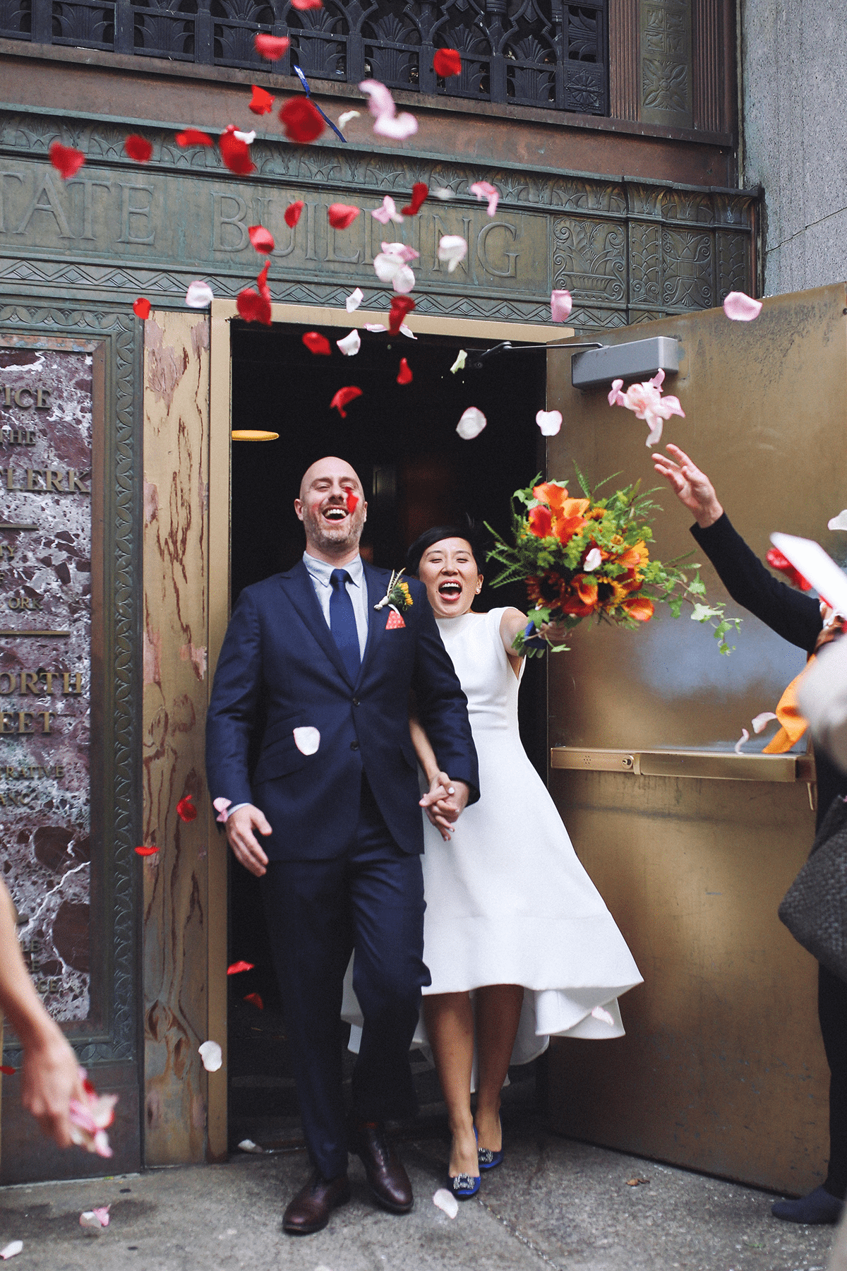 A couple exits their wedding ceremony with flower petals being thrown