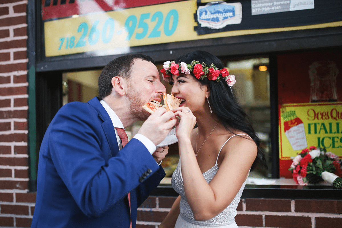 a wedding couple share the same slice of pizza 