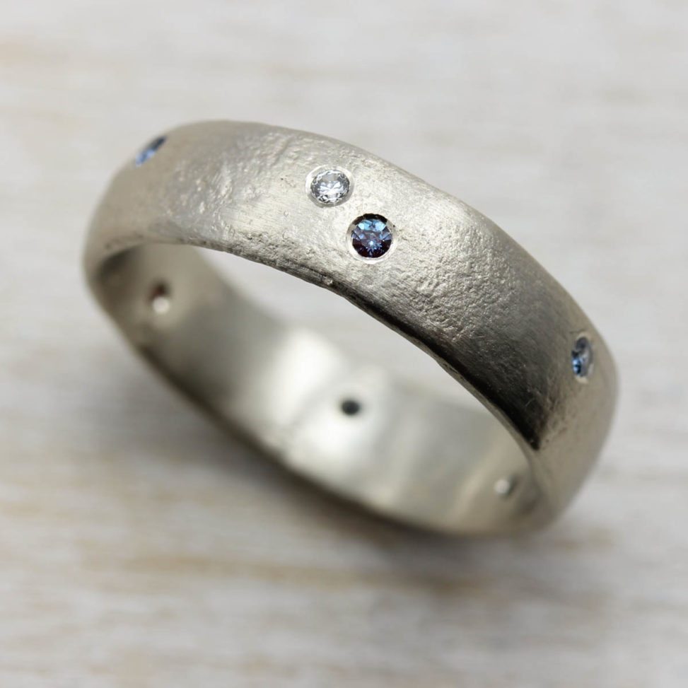 thick band ring with blue and white gems embedded in it on table
