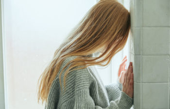 Blond woman with her head against the wall