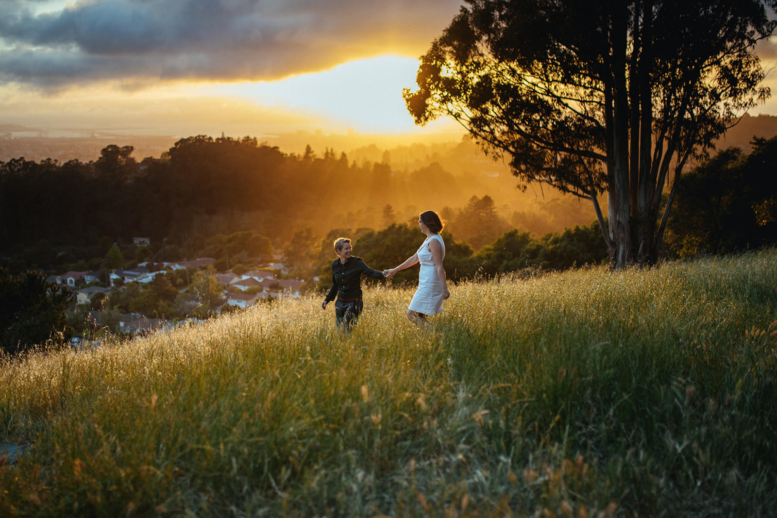 A couple in love walk down a hillside as a ridiculously beautiful sun sets behind them