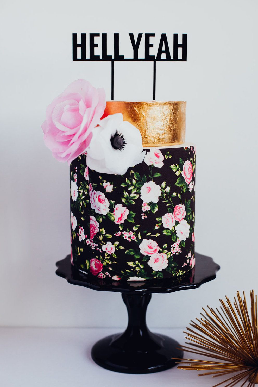 typography topper that says hell yeah on a gold and floral print tiered cake