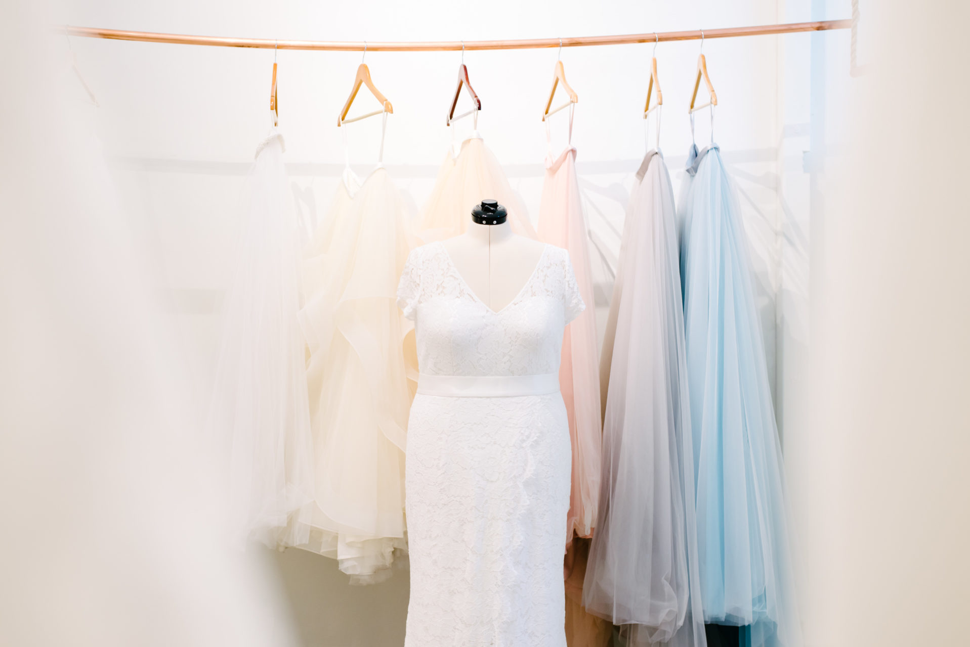 a selection of skirts hang behind a wedding dress on a form