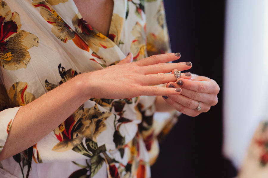 Woman in floral robe places ring on her right ring finger