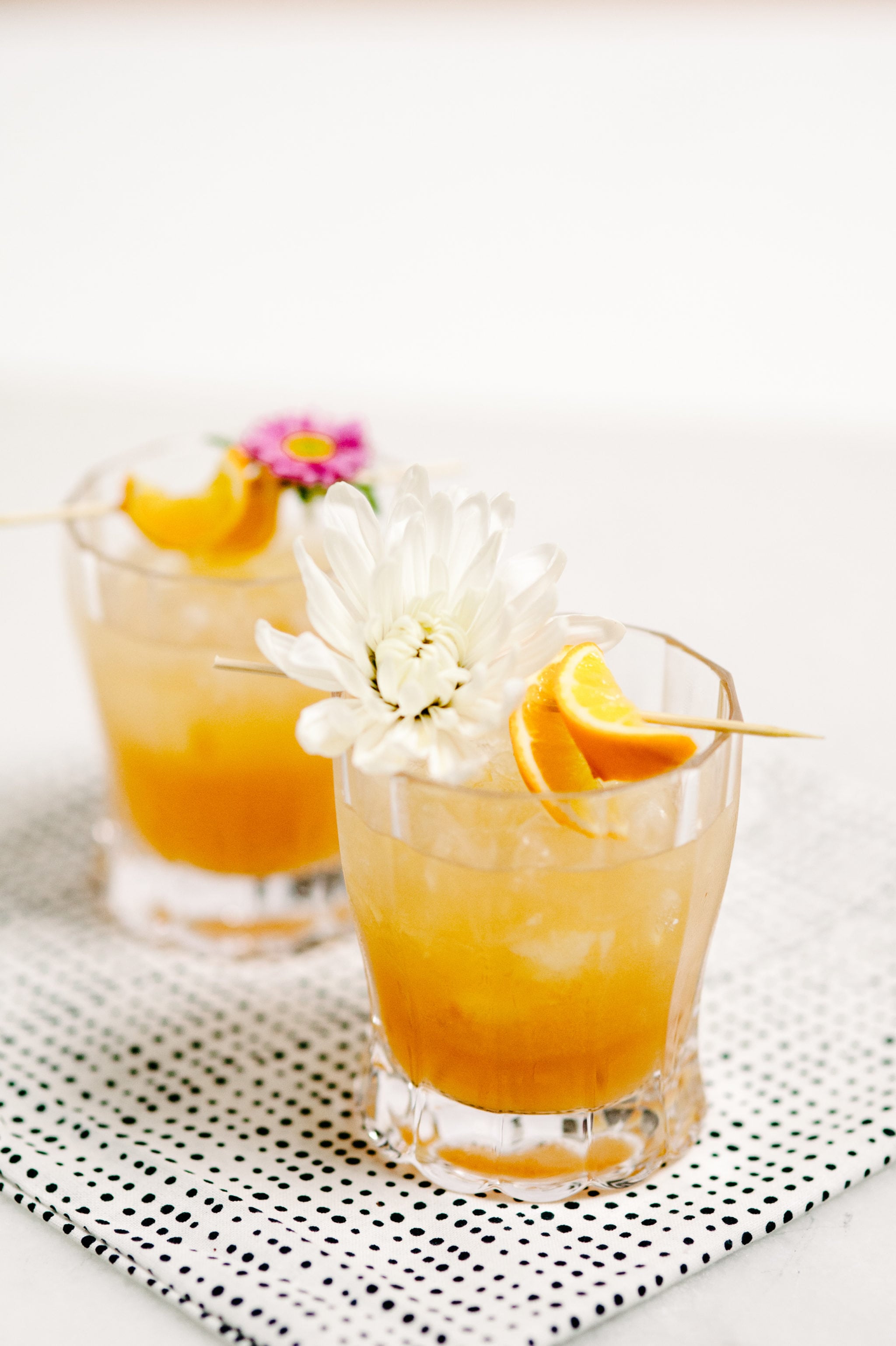 orange colored cocktails with flower and citrus garnish