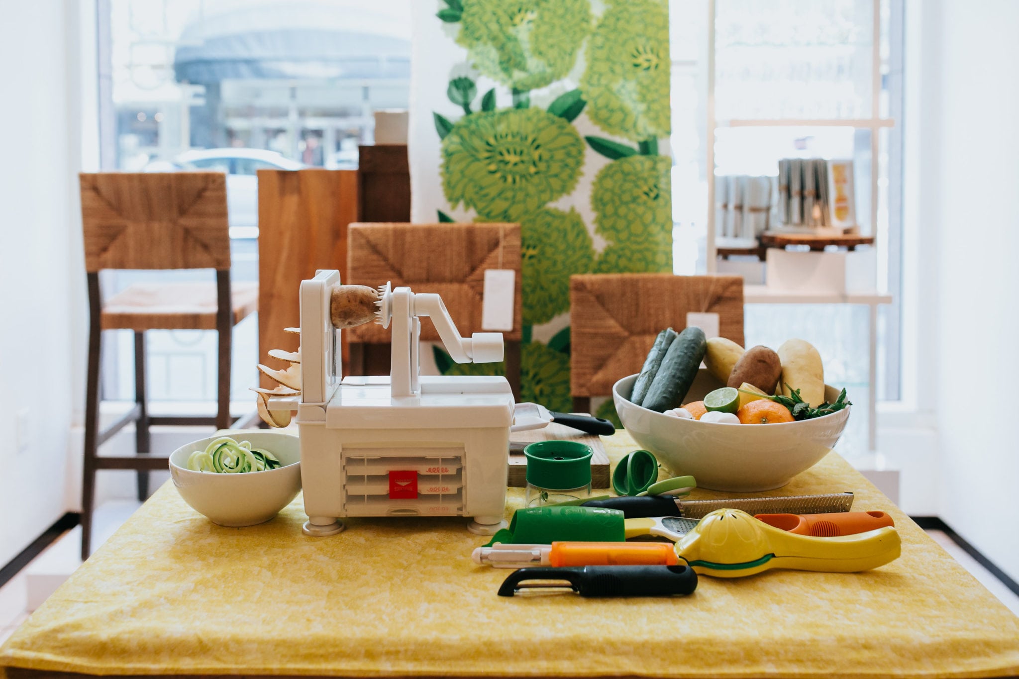 a crate and barrel vegetable spiralizer on a table surrounded by fresh vegetables