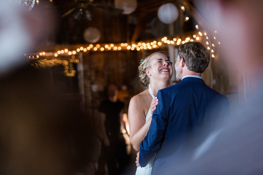 a bride laughs while dancing with her groom