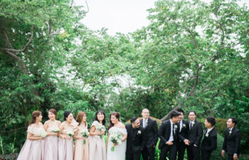 A wedding party lines up in front of trees