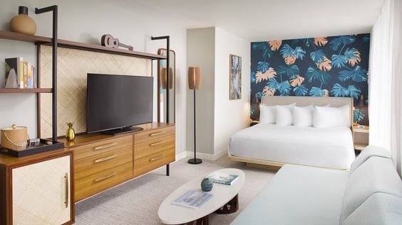 Mid century modern styled hotel room with tropical wallpaper
