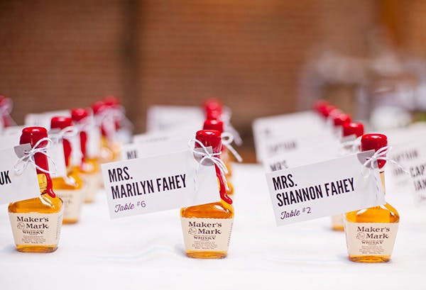 Close up of small single use Maker's Mark bottles with names attached as table assignments