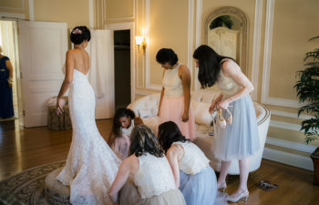 Wedding party adjusting bridal train in front of a mirror