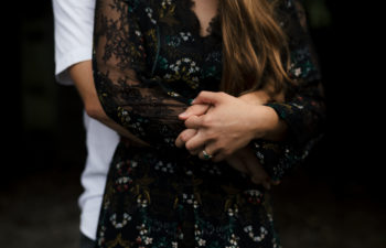 Couple standing together, hands intertwined.