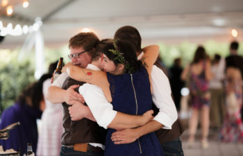 A group of people embrace while at a wedding reception
