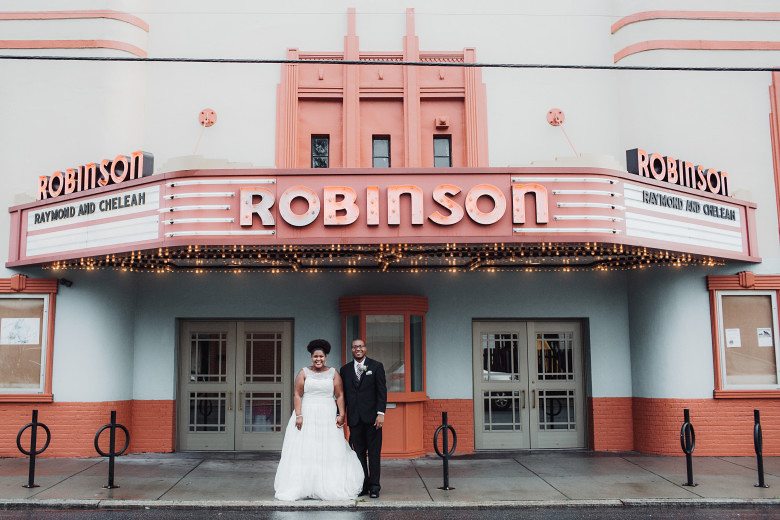 wedding couple standing under a sign that says Robinson