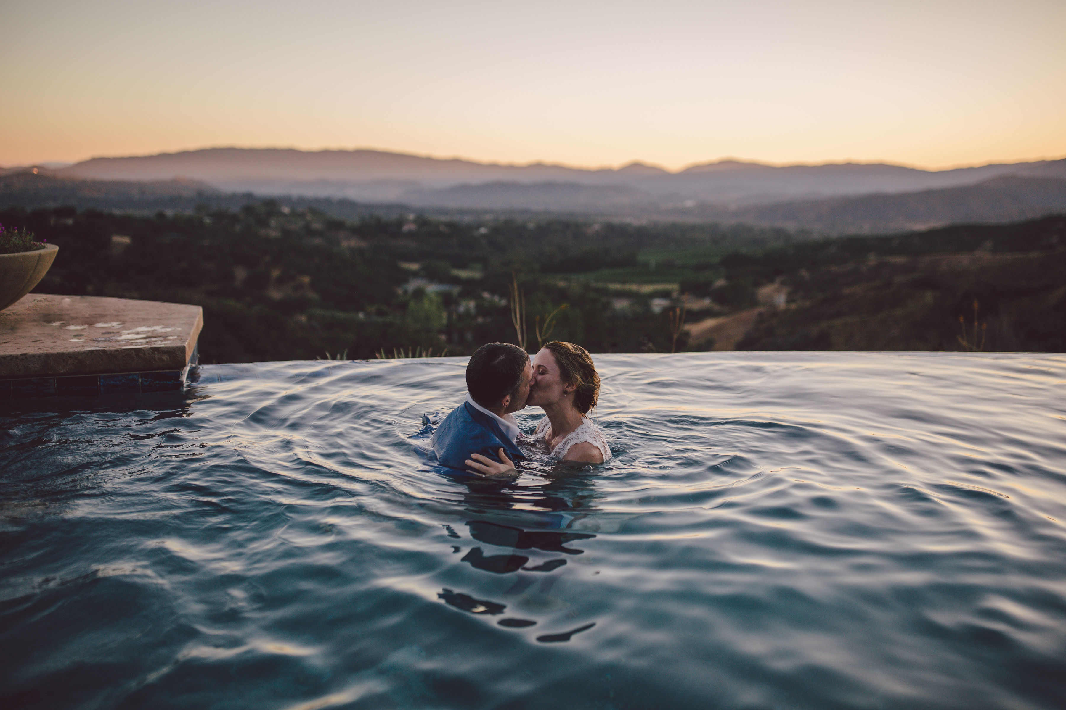 two people kiss in a pool overlooking a valley