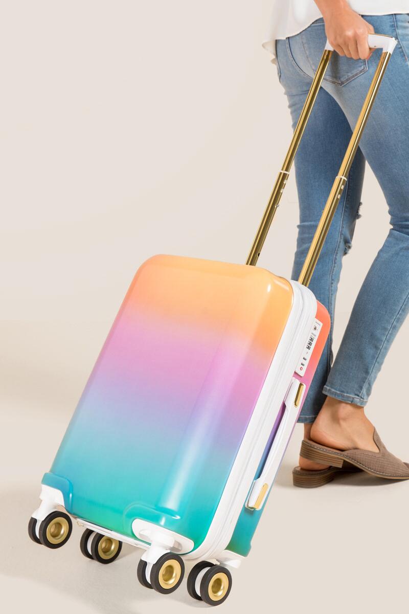 A woman pulling a pastel rainbow carry on luggage