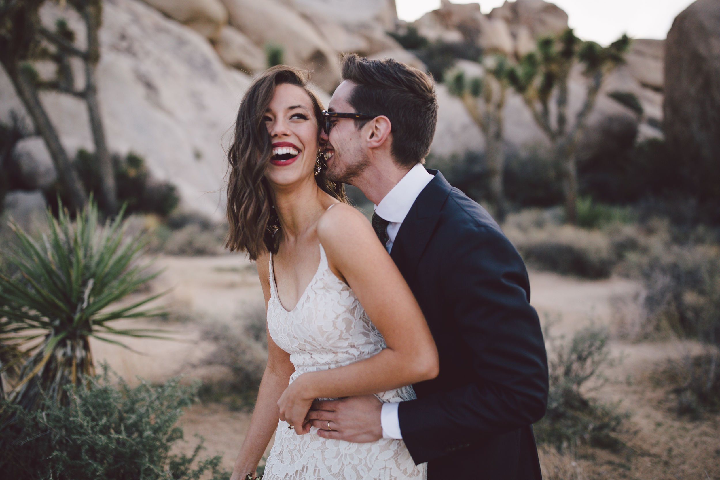 Two people laugh and embrace while in a California desert