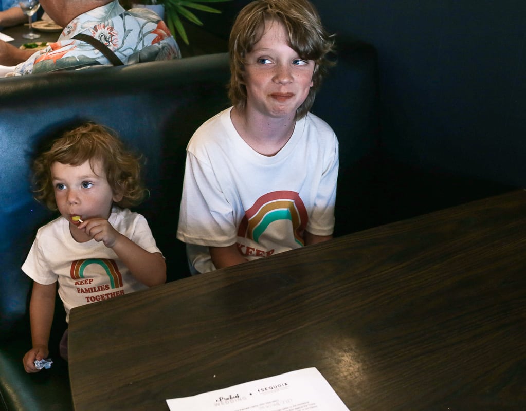 Two children sit in a restaurant booth