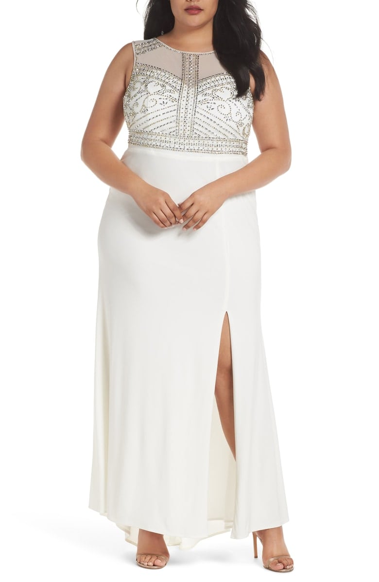 A woman wears a white column dress with high slit and beaded empire bodice