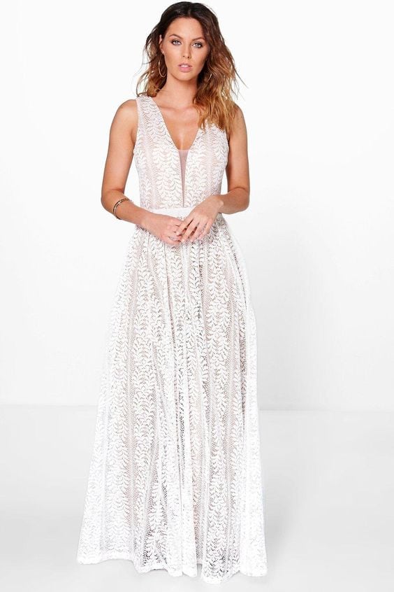 A woman wears a white lace sleeveless dress with deep v-neck and a large fern lace motif