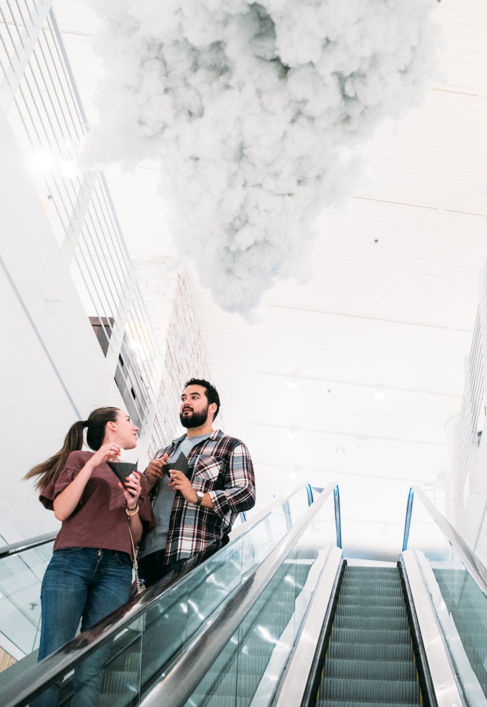 Two people riding and escalator beneath a cloud installation at the crate and barrel san francisco private registry event with a practical wedding
