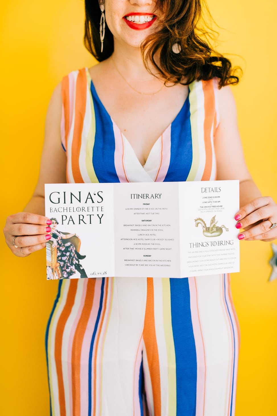 A woman in a striped jumpsuit smiles and holds a tri-fold full-color itinerary that reads "Gina's Bachelorette Party"