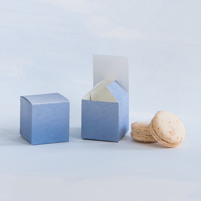 blue favor boxes from minted alongside two french macrons
