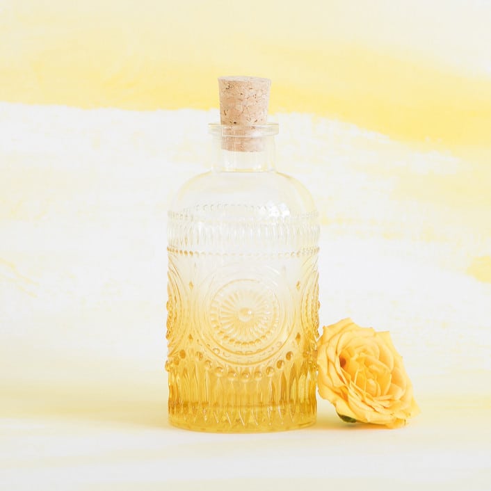 yellow and clear ombre deco bottle with cork from Minted, pictured with a yellow flower