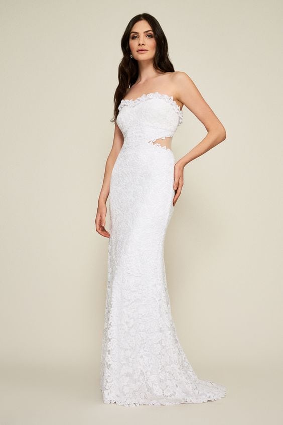 A woman wears a strapless lace white dress with peek-a-boo cutout sides