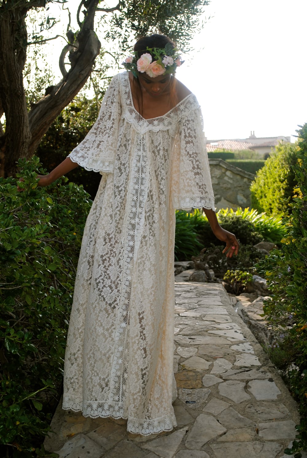 A woman wears a loose-fitting white lace dress with large bell sleeves