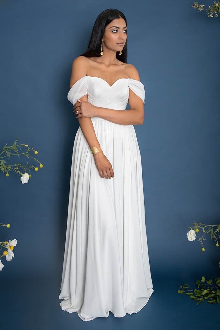a woman wears a white dress with off-the-shoulder cap sleeves and a cross-front bodice