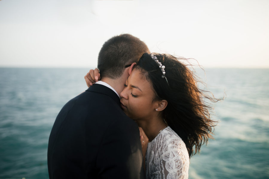 a couple in wedding clothes embraces in front of the sea
