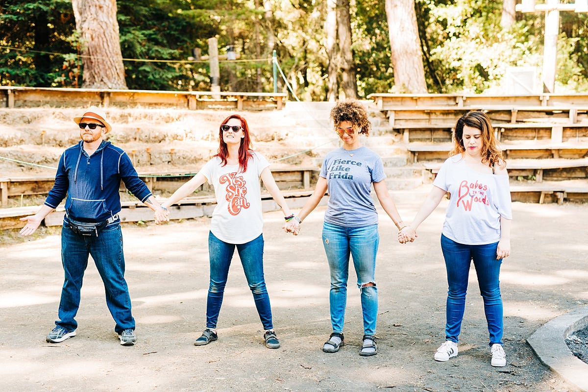 Camp leaders standing and holding hands, eyes closed at the compact summer camp in la Honda, CA
