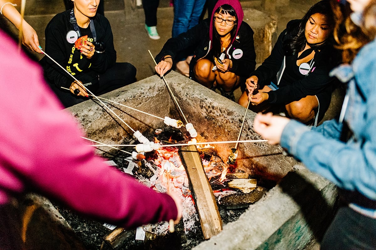 women roasting marshmallows over a bonfire at the compact summer camp in la Honda, CA