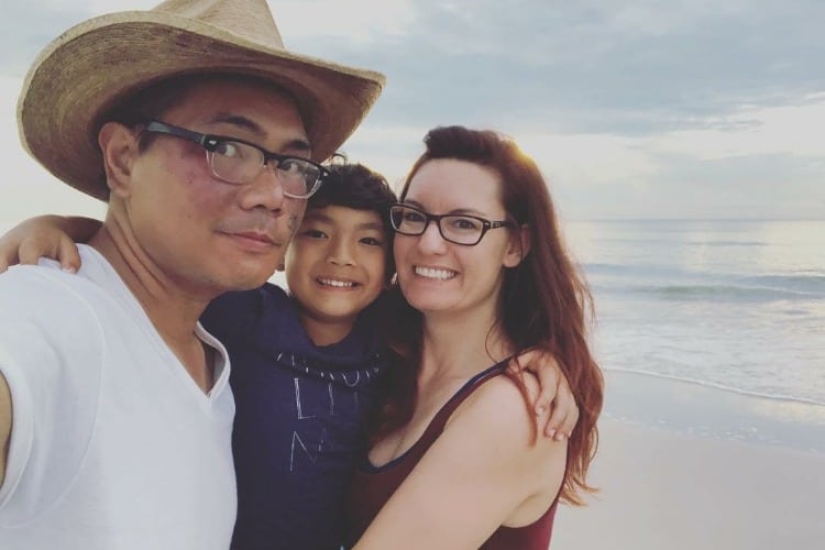man with cowboy hat talking a selfie with a redheaded woman and little boy at the beach