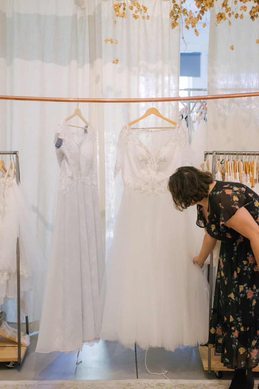 A woman looks at wedding dresses on a hangar