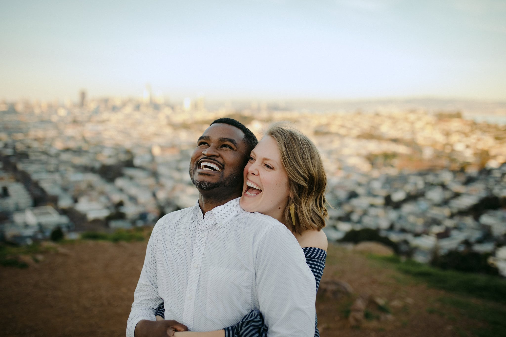 a couple laughs together on a hill