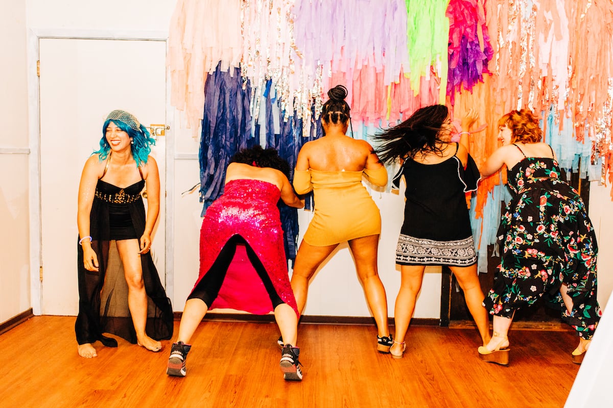 5 women shaking their booties and laughing on the dance floor