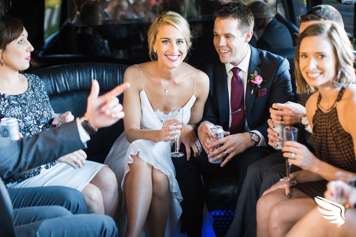People in formal clothes drinking champagne in a skedaddle limo-like bus