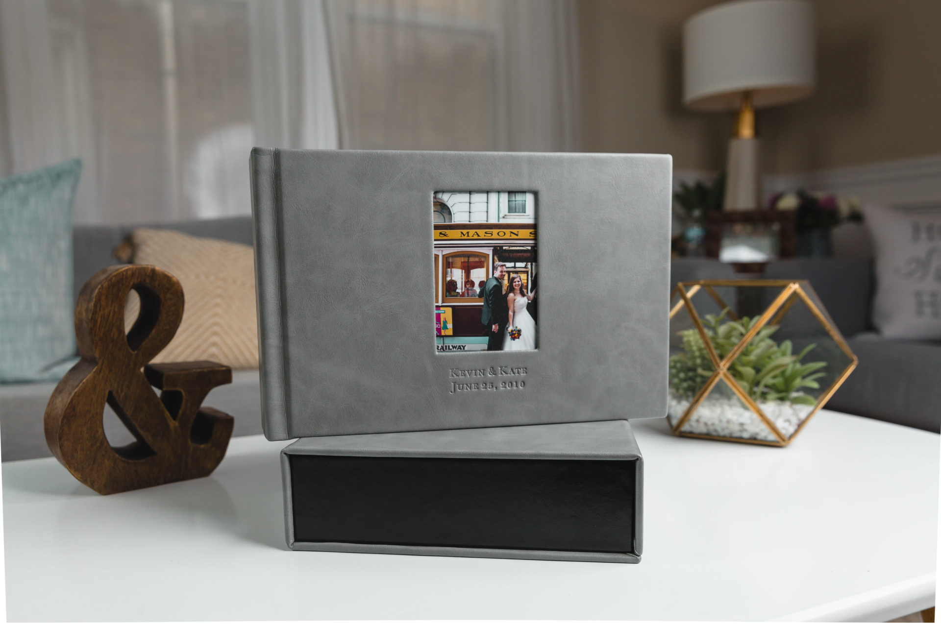 A grey wedding album and it's matching box from Albums Remembered sits on a white coffee table