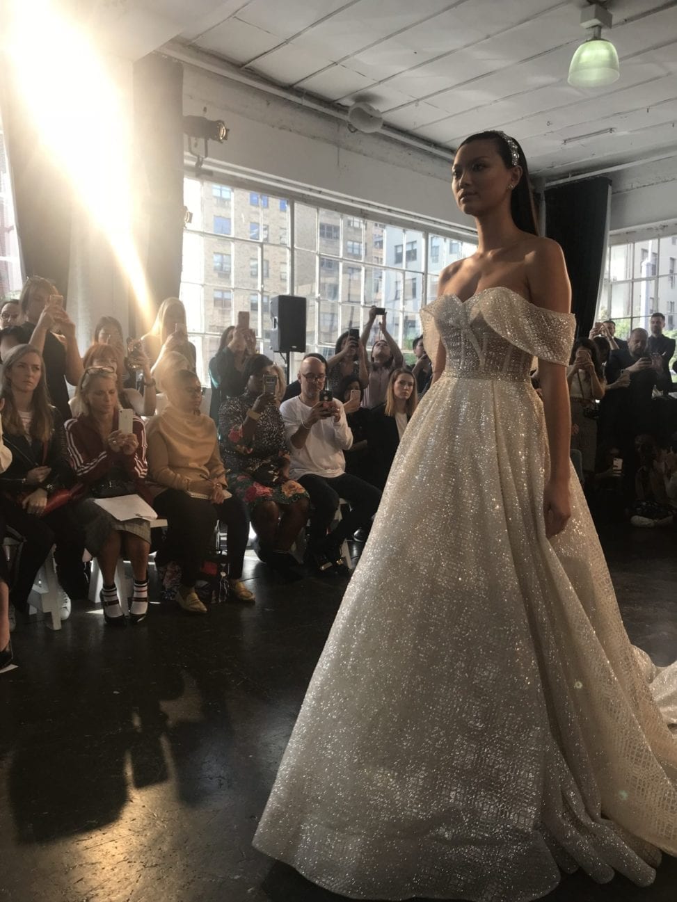 An ethnically Asian model walks the runway in a sparking off the shoulder white wedding dress in Berta 2019 fall/winter show at New York Bridal Fashion Week