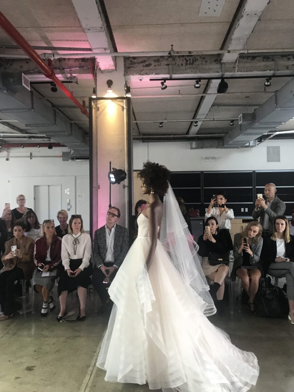 An African-American model walks the runway in a strapless wedding dress with veil in the Watters 2019 fall show at New York Bridal Fashion Week